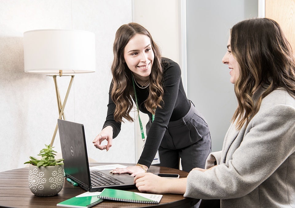 Woman helping someone on a laptop