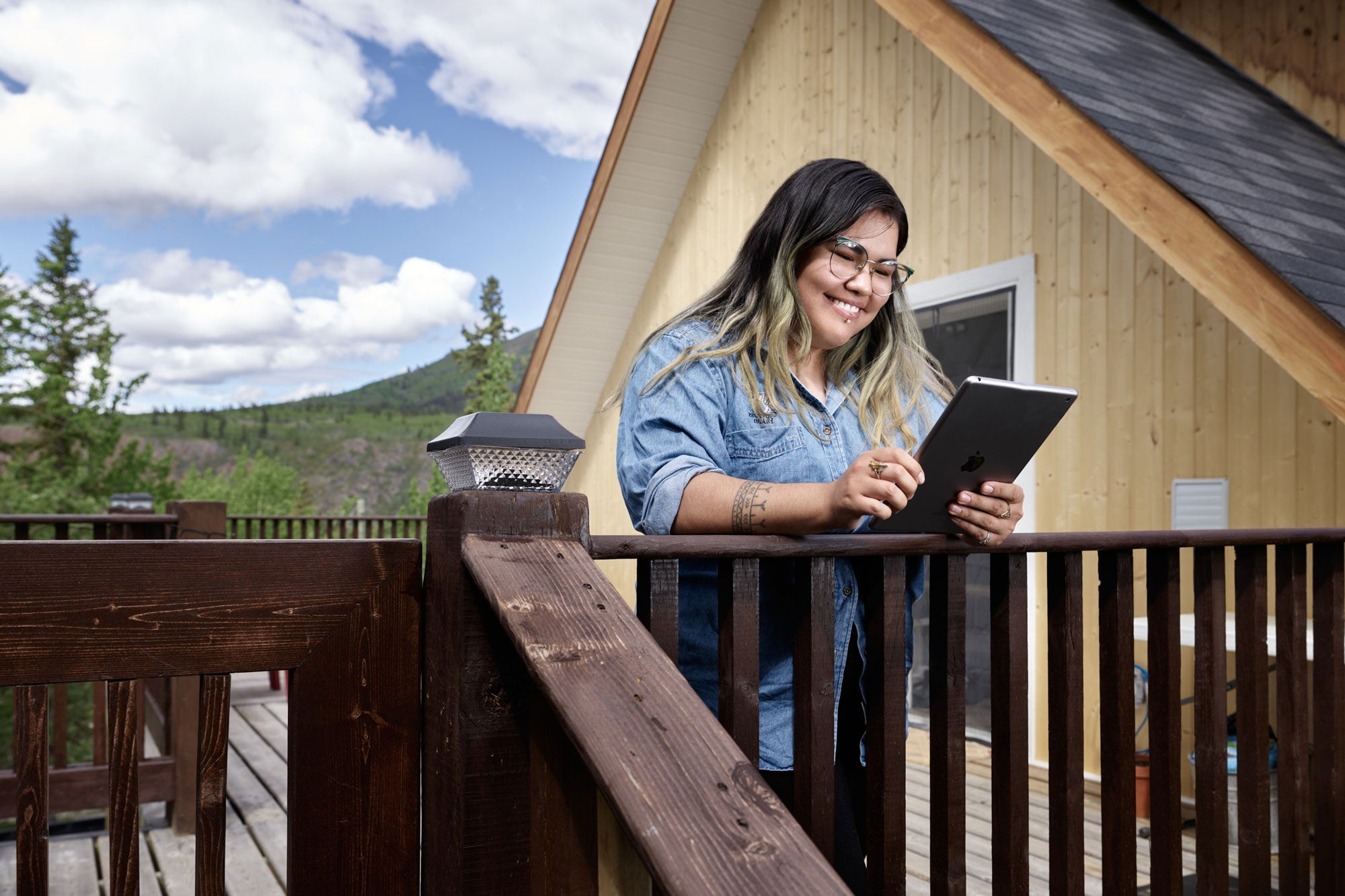 An Indigenous woman smiles while using a tablet computer.