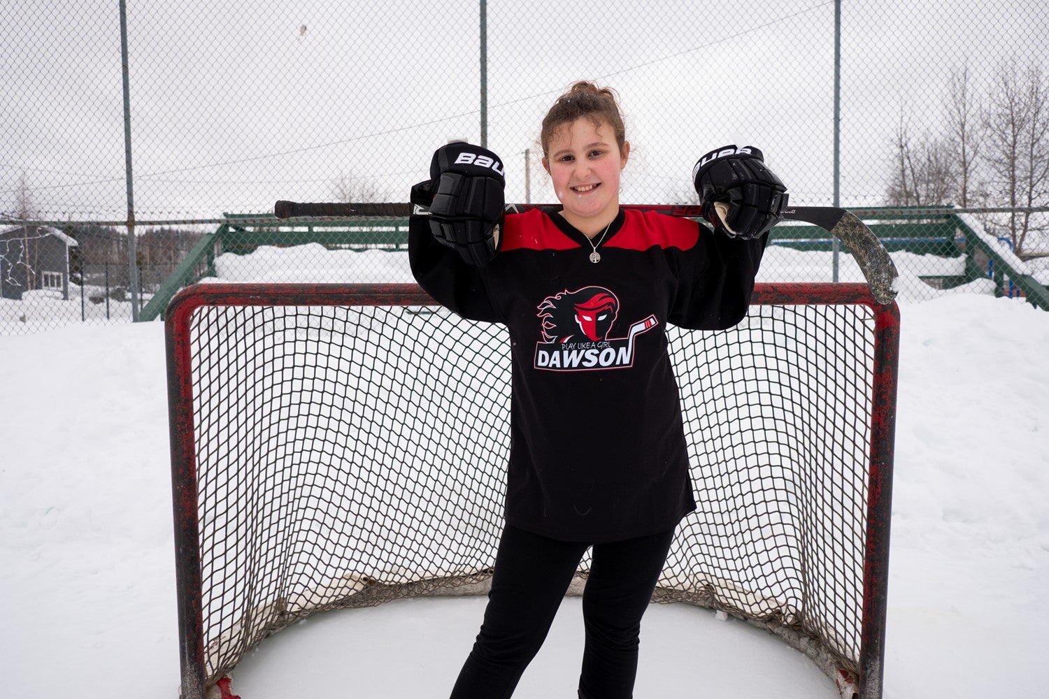 Emery stands in front of a net with her hockey stick