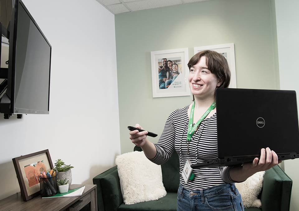 Portrait of Kathleen as she holds a laptop and smiles