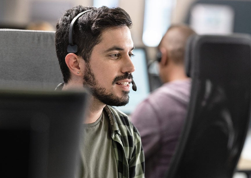 Sales Representative smiling while talking to a customer through a headphone