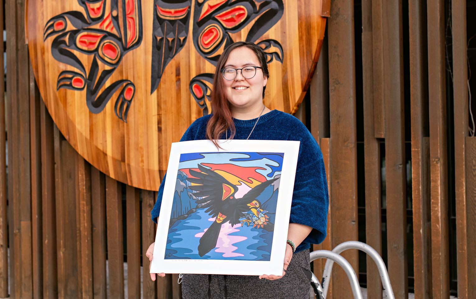 Kayla Smith-Clarke standing with her digital directory art winner, the Crow and the Native Spirit