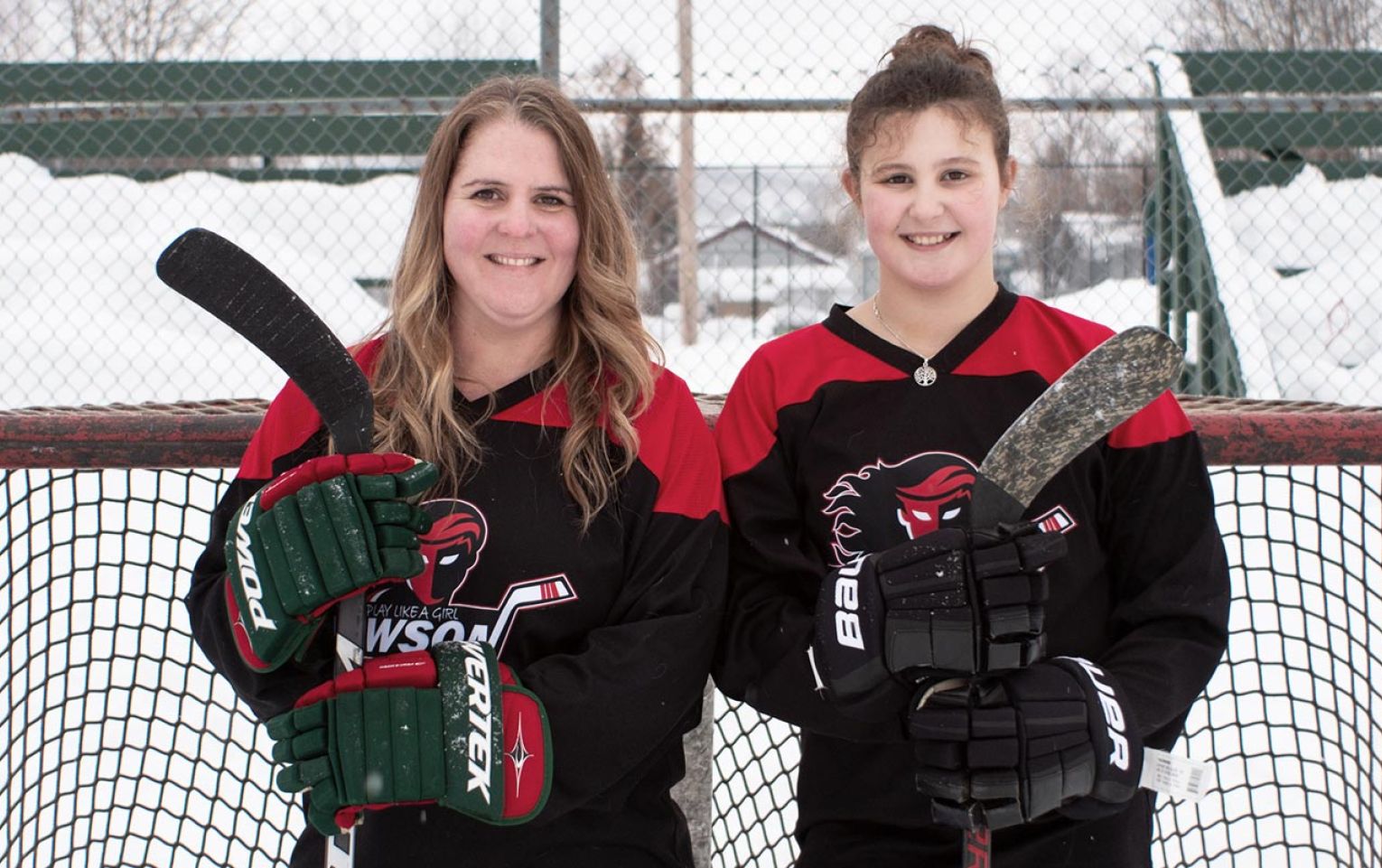 Megan and her daughter Emery standing in front of a hockey net