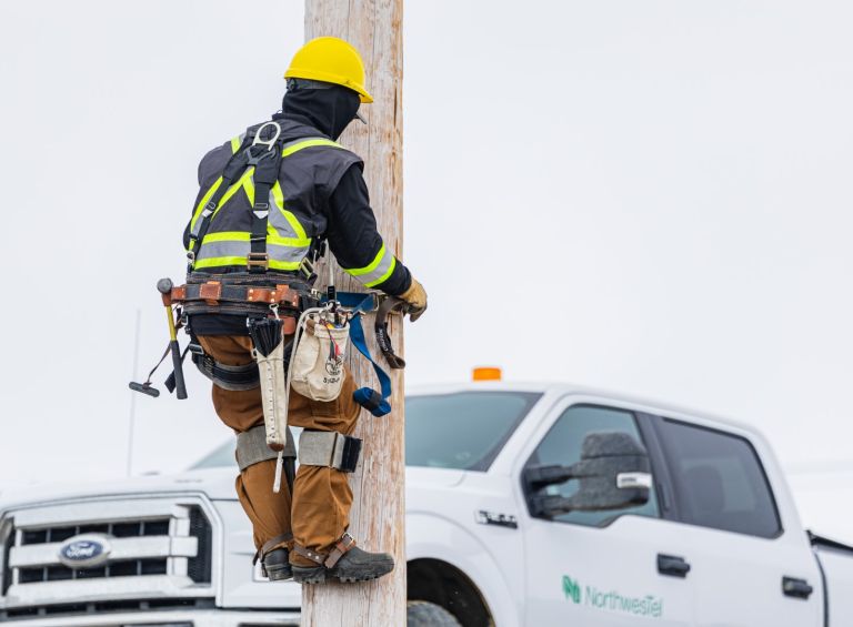 Northwestel technican climbing roadside pole